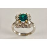 An 18ct white gold emerald and diamond cluster ring, central rectangular deep green emerald,