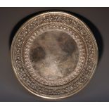 An Indian/Burmese silver circular dish, chased with borders of leafy scrolls and lotus, 25cm diam,