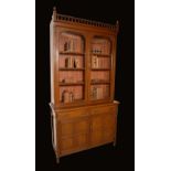 An Aesthetic Movement walnut library bookcase, spindle cornice flanked by urnular finials,