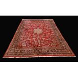 A large hand woven rug, geometric designs in hues of cobalt, steel grey and cream on a red ground,