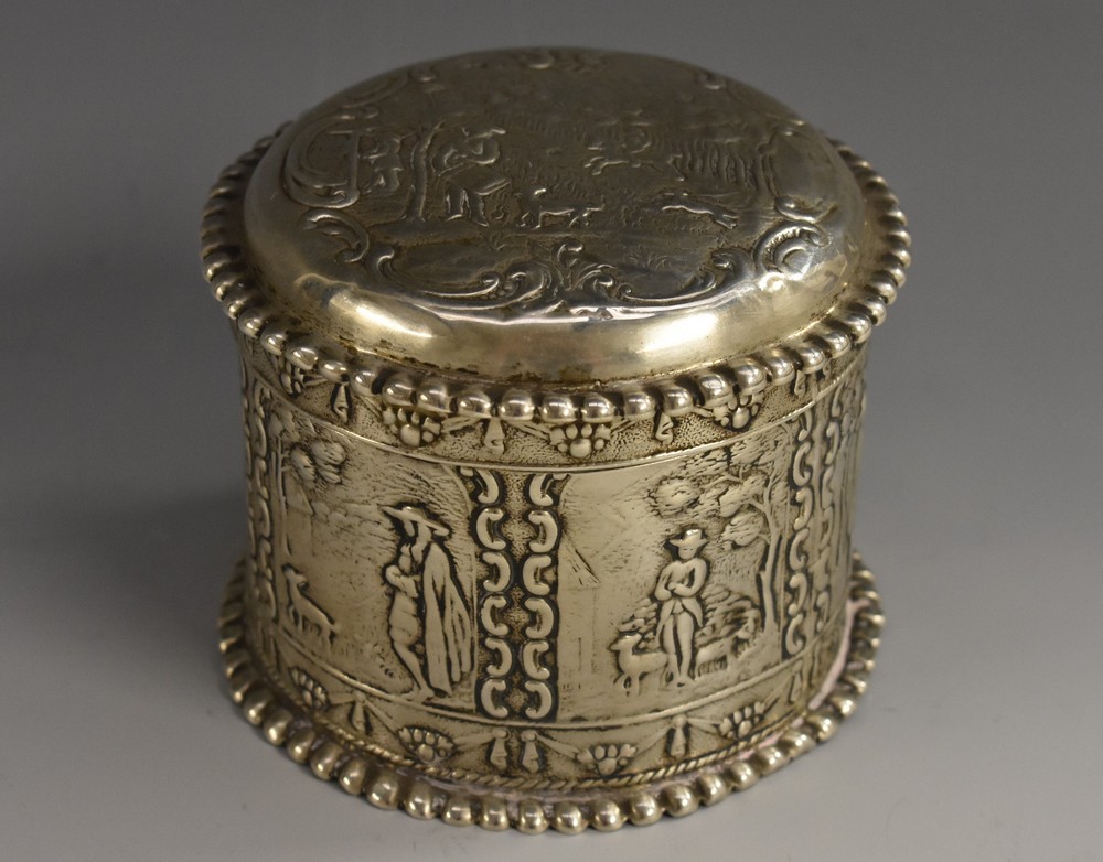 A Dutch silver circular box and cover, chased with figures in 18th century dress,