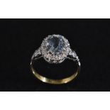 A diamond and pale blue stone cluster ring, central oval pale blue stone possibly topaz,