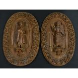 A pair of large Indian hardwood wall panels, each boldly carved with a deity within a temple arch,