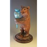 A Black Forest bear, he stands, holding an epergne flute, carved socle, circular base, 25.