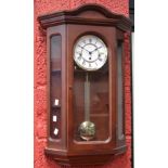 A reproduction Franz Hermle chiming wall clock, canted glazed door, white dial, bold Roman numerals,