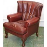 A modern leather wingback armchair, cabriole legs, ball and claw feet.