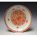 A Chinese dish, decorated in in red with lotus and scrolling foliage, the rim with bats,