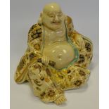 A 19th century Japanese figure of a reclining Hotei in flowing robes, picked out in gilt,