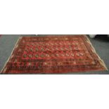 A Malayan rug, triple rows of Guls, guard stripes, in tones of red,