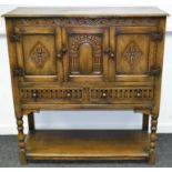 An oak Old Charm style cabinet, moulded top, foliate carved frieze,