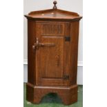 A Priory style oak floor standing corner cupboard of small proportions, finialled gallery,