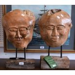 A pair of carved wooden decorative masks on stands