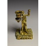 A post-Regency figural so-to-bed taperstick, cast with a young urchin holding a sconce,