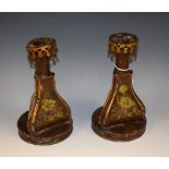 A pair of 19th century toleware triform candlesticks, painted with sprays of flowers,