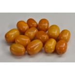 Amber Beads - a collection of thirteen slightly graduated oval beads,