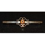 A classical design bar brooch, central inset with a single orange stone, probably a citrine,