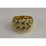 A diamond and emerald accented lattice work dress ring, yellow metal shank, stamped 750, size L, 7.