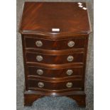 A reproduction mahogany serpentine front small chest of drawers