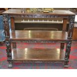 An oak three tier buffet, moulded tiers, the friezes carved with floral roundels,