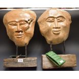 A pair of carved wooden decorative masks on stands