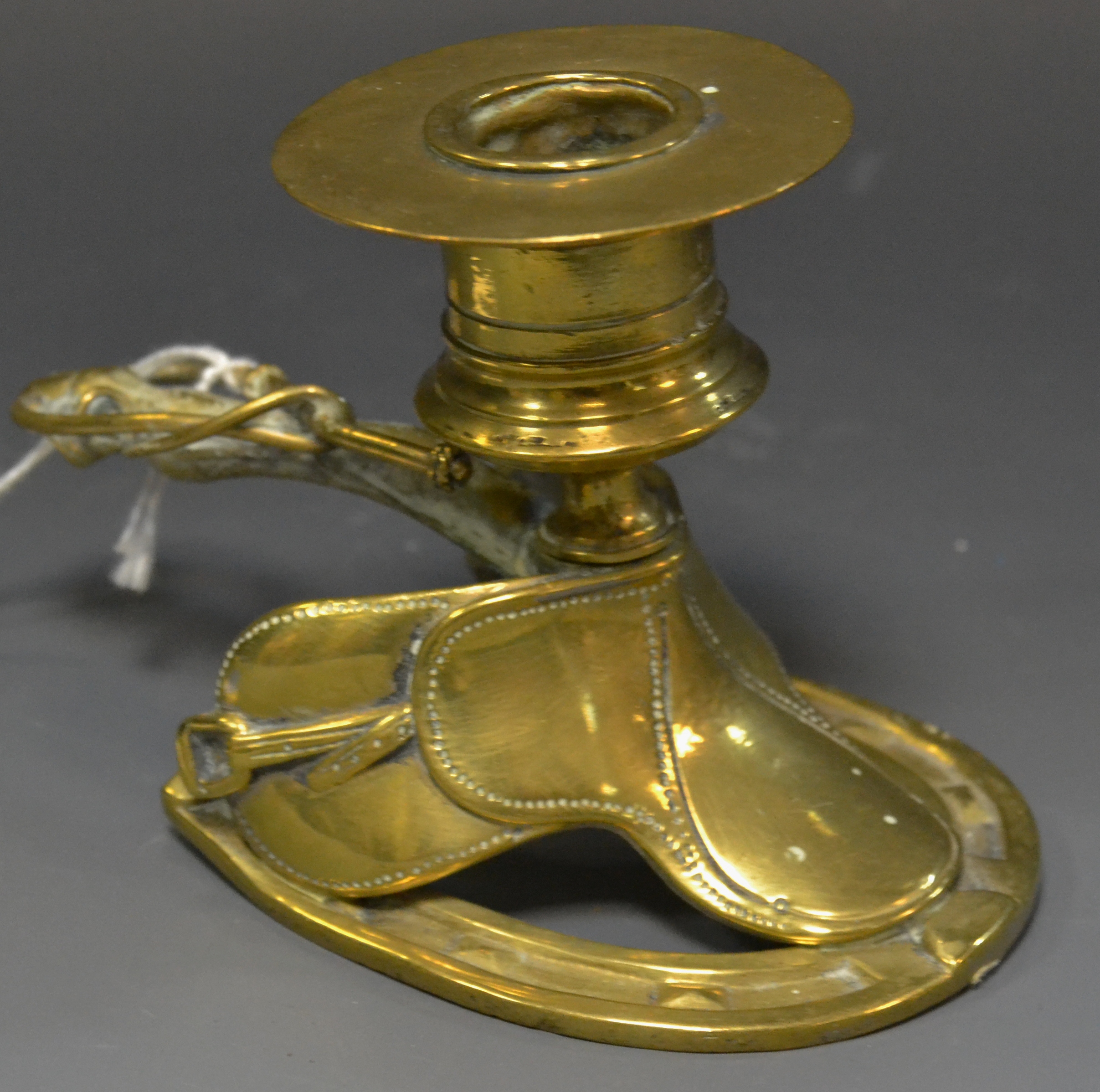 A 19th century brass novelty novelty chamber stick, cast as a saddle,