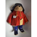 A Gabriel Designs Paddington Bear stuffed toy, red coat, blue hat and wellington boots,