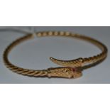 A 9ct gold snake head bangle in the Etruscan style.