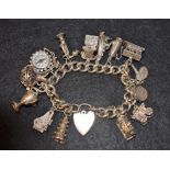 A silver charm bracelet set with fourteen charms, including caravan, piano, compass, telephone, etc.