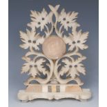 A 19th century alabaster pocket watch stand, pierced and carved with scrolling vine, shaped base,