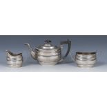 A composed George V silver three piece boat shaped tea service, comprising teapot,