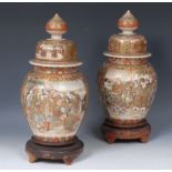 A pair of Japanese Satsuma temple vases and covers, decorated in the typical manner with figures.