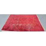 A Middle Eastern rectangular woollen carpet the field with rows of guls and hooked medallions,