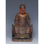 A 19th century Chinese lacquered hardwood carving, of an Immortal, enthroned,