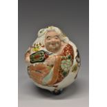 A Japanese Satsuma porcelaineous novelty, of a comic figure, painted in colourful polychrome,