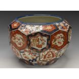 A Japanese Imari hexagonal panelled jardiniere, decorated in the typical palette with trophies,