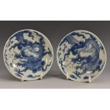 A pair of Chinese circular saucer dishes, each painted in underglaze blue with a ferocious dragon,