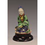An 18th century Chinese porcelain figure, of Guanyin, seated wearing a veil and flowing robes,