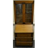 A 1940's oak bureau bookcase, two lead glazed doors to top, fall front over three drawers to base.