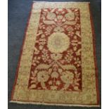 A hand knotted woolen Oriental rug in tones of claret and cream 148 x 87cm