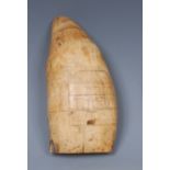 A whale tooth scrimshaw, decorated with a house, a further dwelling to verso, 12cm long,