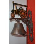 A reproduction cast metal wall mounted bell with traction engine pediment.