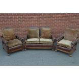 An early 20th century three piece oak bergère suite, each adjusting on a ratchet, wicker sides,