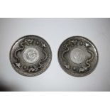 A pair of white metal dishes, cast with dragons surrounding a 'coin',