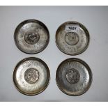 A set of four white metal dishes, inset with 'coins',