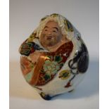 A Japanese Satsuma porcelaineous novelty, of a comic figure, painted in colourful polychrome,