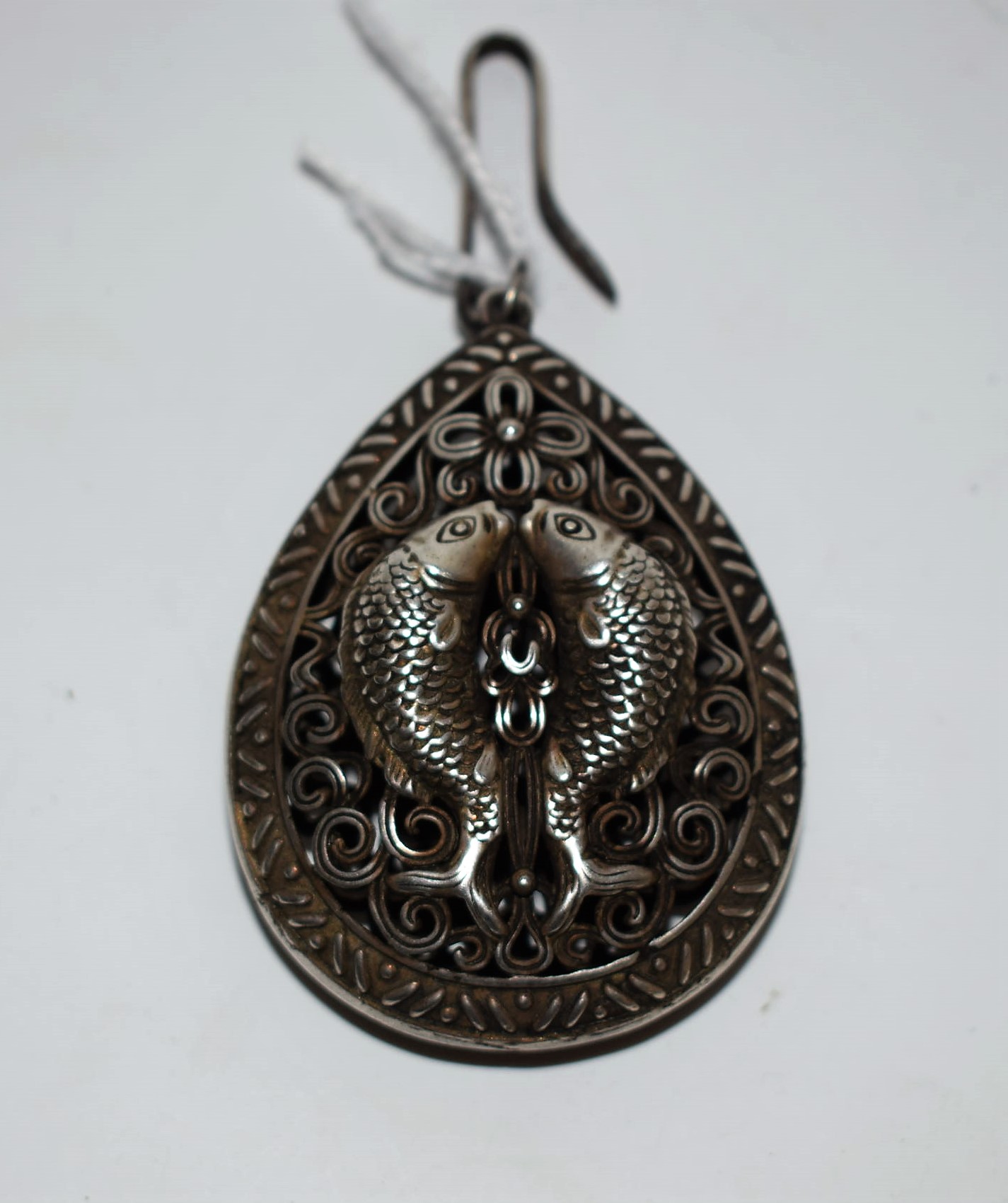 A white metal pierced hollow pear drop pendant, cast with fish, unmarked,