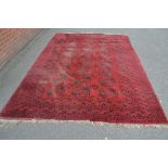 A Middle Eastern rectangular woollen carpet the field with rows of guls and hooked medallions,