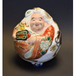 A Japanese Satsuma porcelaineous novelty, of a comic figure, painted in colourful polychrome,