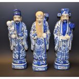 A porcelain figure of a Chinese elder holding a staff; others similar,