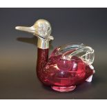 A cranberry glass duck shaped claret jug, white metal mounts,